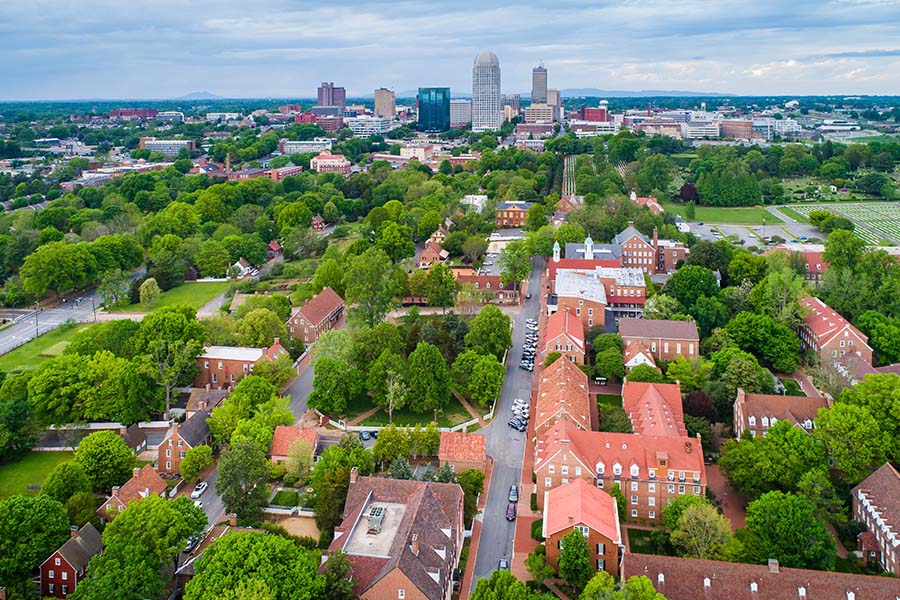 Contact - Aerial View of Old Salem and Downtown Winston-Salem in North Carolina Displaying Many Trees and Buildings
